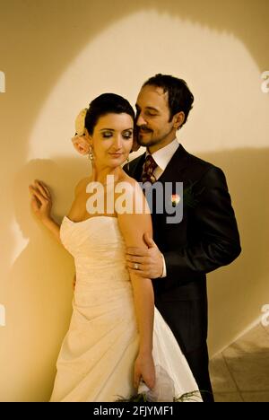 Magnifique couple de mariage (mariée et marié) posé devant le mur blanc. Banque D'Images