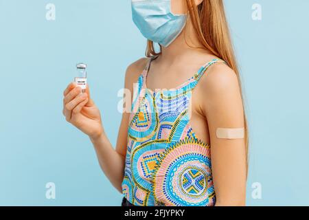 Vaccination d'une petite fille, un petit enfant avec un pansement adhésif sur sa main et tenant une bouteille avec un vaccin contre le coronavirus covid-19, la grippe Banque D'Images