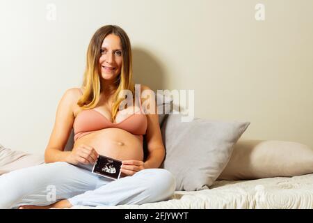 La femme enceinte s'assoit avec l'échographie du bébé à la main Banque D'Images