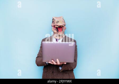 Homme euphorique avec tête de lézard avec ordinateur portable sur fond bleu Banque D'Images