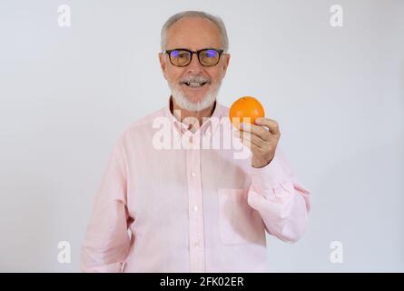 Portrait d'un homme de haut niveau joyeux qui tient orange et souriant. Banque D'Images