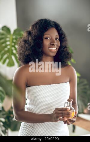 Jeune femme à la peau foncée avec des huiles essentielles à la main Banque D'Images