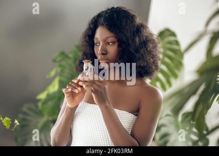 Jeune femme à la peau foncée avec des huiles essentielles à la main Banque D'Images