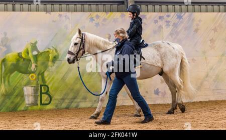 East Lothian, Écosse, Royaume-Uni, 27 avril 2021. Muirfield Riding Therapy rouvre: L'organisme de bienfaisance accueille ses premiers jeunes pour leur séance de thérapie avec des restrictions de verrouillage assouplies. En raison de restrictions continues, seuls les clients plus mobiles peuvent être pris en charge pour le moment. Photo : Nathan, âgé de 10 ans, élève de l'école primaire de yester sur son cheval de thérapie Johnny dirigé par la volontaire Susan Banque D'Images