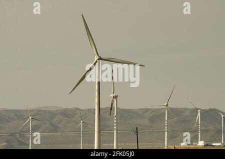 Des éoliennes et des lignes électriques sillonnent le désert à la périphérie ouest de Turpan, dans l'un des endroits les plus chauds de la planète. Les énergies renouvelables éoliennes sont de plus en plus utilisées par les Chinois pour développer leurs industries gourmandes en énergie, comme on le voit ici dans le Xinjiang oriental, en Chine, en RPC. © Time-snapshots Banque D'Images