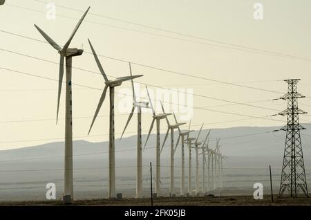 Des éoliennes et des lignes électriques sillonnent le désert à la périphérie ouest de Turpan, dans l'un des endroits les plus chauds de la planète. Les énergies renouvelables éoliennes sont de plus en plus utilisées par les Chinois pour développer leurs industries gourmandes en énergie, comme on le voit ici dans le Xinjiang oriental, en Chine, en RPC. © Time-snapshots Banque D'Images