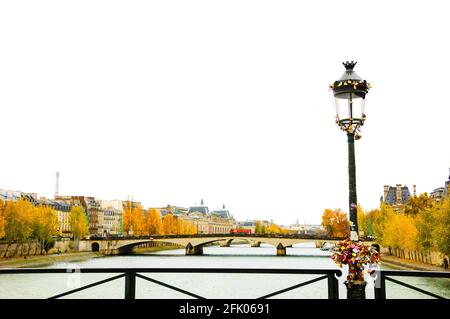 Paris en automne. Le groupe de serrures d'amour est attaché à la lampe de rue. Vue sur la tour Eiffel, les ponts et les arbres dorés du parc de remblai. Banque D'Images