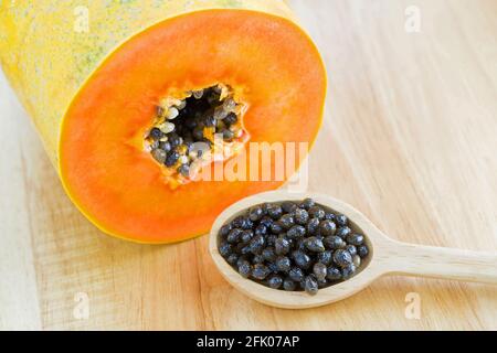 Gros plan des graines de papaye fraîches à côté des fruits de papaye coupés affichage de la texture orange Banque D'Images