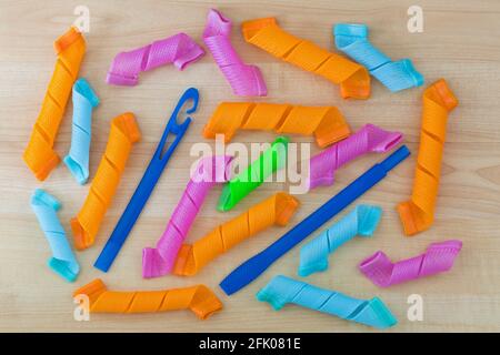 Bigoudis colorés, longues anglaises en spirale, rouleaux à levier avec baguette pour courber rapidement les cheveux sur fond en bois Banque D'Images