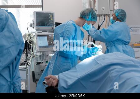 Femme de race blanche chirurgien portant un masque facial mettant le masque d'oxygène sur patient allongé dans le lit Banque D'Images