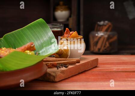 Cornichon au citron, cornichon au citron rouge chaud et aigre dans un traditionnel pot en céramique qui est placé comme plat de côté pour le poulet biryani sur une texture en bois, cuisine b Banque D'Images
