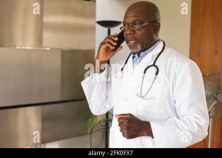 Médecin afro-américain senior parlant sur smartphone à la maison Banque D'Images