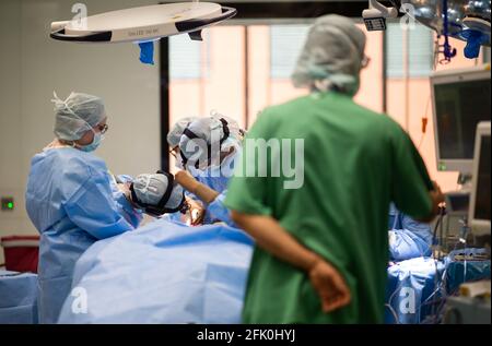 Essen, Allemagne. 27 avril 2021. Une équipe de médecins et d'assistants chirurgicaux se tiennent autour d'un patient pendant une opération dans le bloc opératoire ORL de l'hôpital universitaire. La nouvelle construction de l'aile opérationnelle pour les opérations Eye et ENT a coûté près de 70 millions d'euros. Selon l'hôpital universitaire, ce sont actuellement les salles d'opération les plus modernes d'Allemagne et d'Europe. Credit: Jonas Güttler/dpa/Alay Live News Banque D'Images