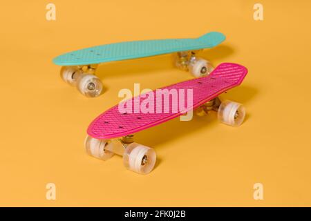 Deux spenny skateboard Rose et vert isolé sur fond jaune Banque D'Images