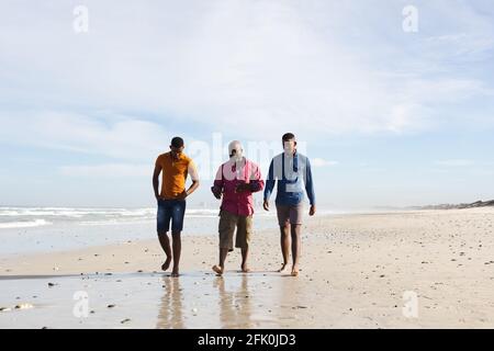 Le père afro-américain et ses deux fils marchent ensemble à la plage Banque D'Images