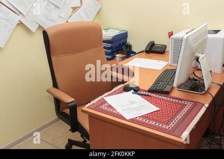 Bureau avec fauteuil en cuir. Un endroit confortable pour travailler avec un ordinateur de bureau, une imprimante et des fournitures de bureau. Banque D'Images