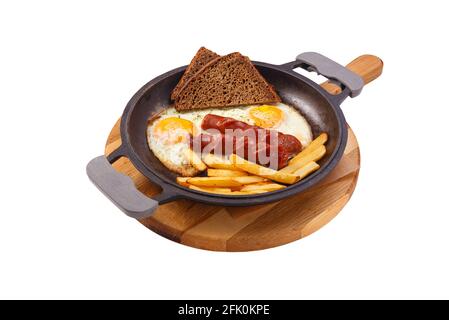 Petit-déjeuner anglais dans une poêle avec des œufs frits, des saucisses, des frites et du pain sur un support en bois isolé sur fond blanc Banque D'Images