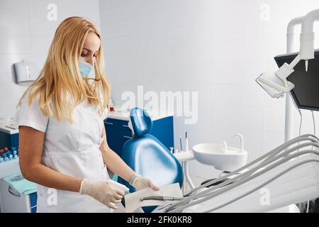 Femme traitant la pièce à main dentaire avec le liquide de nettoyage Banque D'Images