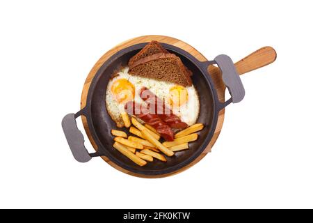 Petit-déjeuner anglais dans une poêle avec des œufs frits, des saucisses, des frites et du pain sur un support en bois isolé sur fond blanc Banque D'Images