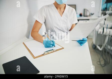 Dentiste femme lisant des radiographies et écrivant des notes Banque D'Images