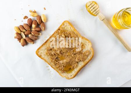 Sandwich au beurre de cacahuète biologique avec miel et arachides sur fond blanc, concept de photographie alimentaire Banque D'Images