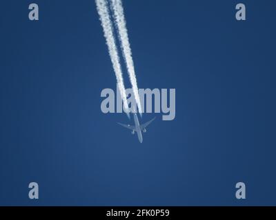 Télé gros plan d'un avion de ligne volant à haute altitude dans un ciel bleu clair avec des contrails Banque D'Images