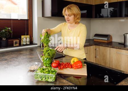 Jeune femme, mère et femme préparant une salade de légumes frais pour sa famille en cuisine.concept de nutrition saine et appropriée. Nourriture végétalienne Banque D'Images