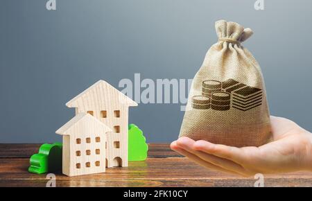 Sac d'argent, figures de bâtiments résidentiels sur un fond gris. Acheter achat et vente, location de logements. Propriétaires communautaires d'appartements. Construction Banque D'Images