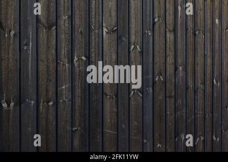 Texture de la paroi sombre de la grange en bois scié brut fait maison. Planches nouées traitées avec du vernis et du goudron de pin. Banque D'Images