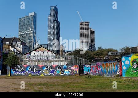 Les bâtiments modernes de haute élévation s'élèvent au-dessus de la périphérie en relief graffitti Allen Gardens à Shoreditch Londres Banque D'Images