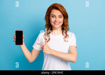 Photo portrait d'une fille pointant le doigt vers l'espace vide de téléphone isolé sur fond bleu pastel Banque D'Images