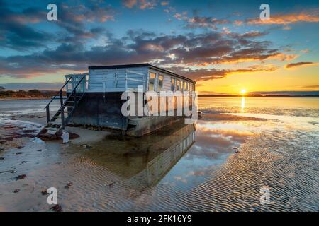 Coucher de soleil stupéfiant sur une ancienne péniche amarrée à Bramble Bush Baie à Studland sur l'île de Purbeck Banque D'Images