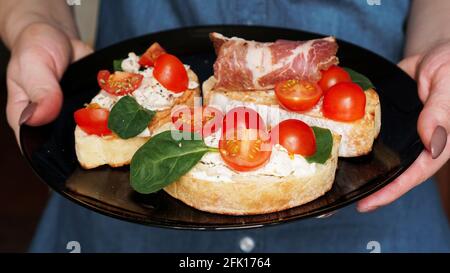 Femme serveur tenant un plateau en bois avec bruschetta dans elle main Banque D'Images