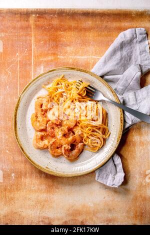 Pâtes à spaghetti à la tomate avec crevettes à la sauce et au parmesan fromage servi dans une assiette en céramique à pois avec fourchette et tissu serviette de table en pierre brune Banque D'Images