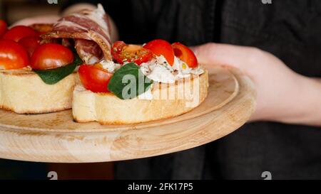 Femme serveur tenant un plateau en bois avec bruschetta dans elle main Banque D'Images