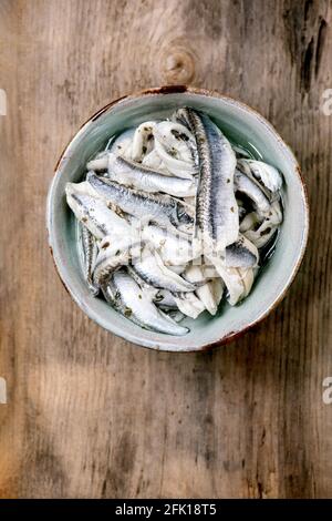 Bol d'anchois marinés ou filet de sardines dans l'huile avec des herbes pour tapas ou antipasti sur fond de bois ancien. Flat lay, espace de copie Banque D'Images