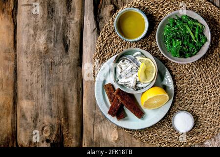 Bol d'anchois marinés ou filet de sardines dans l'huile, servi avec du citron, de l'huile d'olive, du sel et du pain de seigle grillé pour des tapas ou des antipasti, algues Wakame Banque D'Images