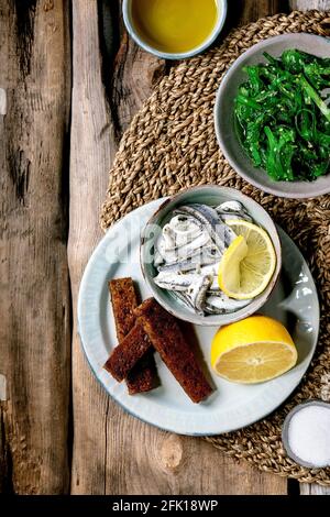 Bol d'anchois marinés ou filet de sardines dans l'huile, servi avec du citron, de l'huile d'olive, du sel et du pain de seigle grillé pour des tapas ou des antipasti, algues Wakame Banque D'Images