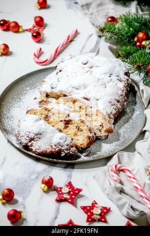 Traditionnel maison de Noël allemand pâtisserie pain de gâteau de stollen sur l'assiette avec des décorations de Noël et des branches de sapin sur fond de marbre blanc. Banque D'Images