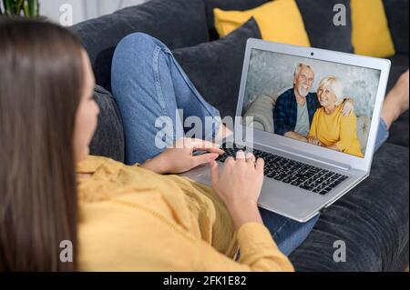 Grands-parents communiquant avec la petite-fille adulte par vidéoconférence, réunion virtuelle avec un grand-père senior et une grand-mère. Couple d'âge mûr sur l'écran de l'ordinateur portable discutant en ligne avec une fille adulte Banque D'Images