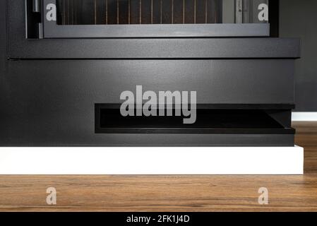 Prise d'air dans une cheminée moderne avec une chambre de combustion fermée dans la salle de séjour, peinte en noir. Banque D'Images