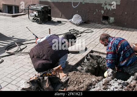 Dnepropetrovsk, Ukraine - 03.26.2021: Les travailleurs des services de distribution d'eau ouvrent un ancien trou d'homme et remplacent les vieux tuyaux rouillés par de nouveaux. Banque D'Images