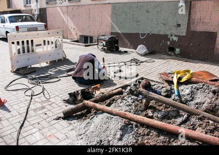 Dnepropetrovsk, Ukraine - 03.26.2021: Les travailleurs des services de distribution d'eau ouvrent un ancien trou d'homme et remplacent les vieux tuyaux rouillés par de nouveaux. Banque D'Images