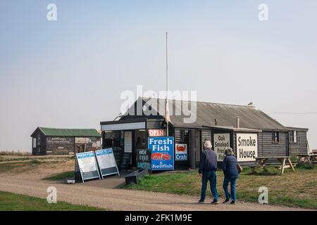 Poissons du Suffolk d'Aldeburgh, vue sur les personnes marchant sur le chemin du front de mer à côté des cabanes de poissons frais situées le long de la plage à Aldeburgh, Suffolk, Royaume-Uni. Banque D'Images