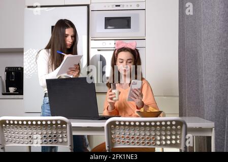 Deux amis dans une cuisine se rattraper et s'amuser tout en étudiant sur un ordinateur portable. Formation à distance. Banque D'Images