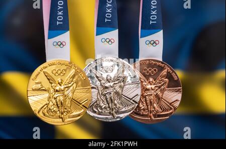 25 avril 2021 Tokyo, Japon. Médailles d'or, d'argent et de bronze des XXXII Jeux Olympiques d'été 2020 à Tokyo, sur fond de drapeau de la Suède. Banque D'Images