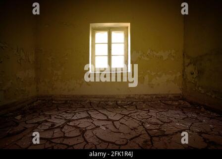 Intérieur de la chambre dans une maison abandonnée avec de la poussière séchée fissurée le sol et la vieille peinture pelée sur les murs Banque D'Images