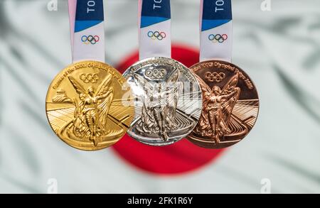 25 avril 2021 Tokyo, Japon. Médailles d'or, d'argent et de bronze des XXXII Jeux Olympiques d'été 2020 à Tokyo, sur fond de drapeau du Japon. Banque D'Images