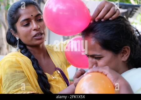 Gros plan de deux amies indiennes qui soufflent des ballons et préparez-vous pour la fête Banque D'Images