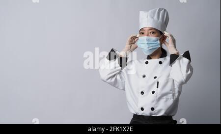 Chef portant un masque médical ou un respirateur de protection du visage pour la protection contre les maladies virales. Sécurité alimentaire et pandémie de coronavirus. Chef posant geste r Banque D'Images